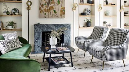 Living room with white walls, alcoves, gray fireplace, green sofa, black coffee table, checked chairs