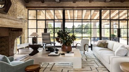 living room with steel framed windows and fireplace with square coffee table with wooden beams